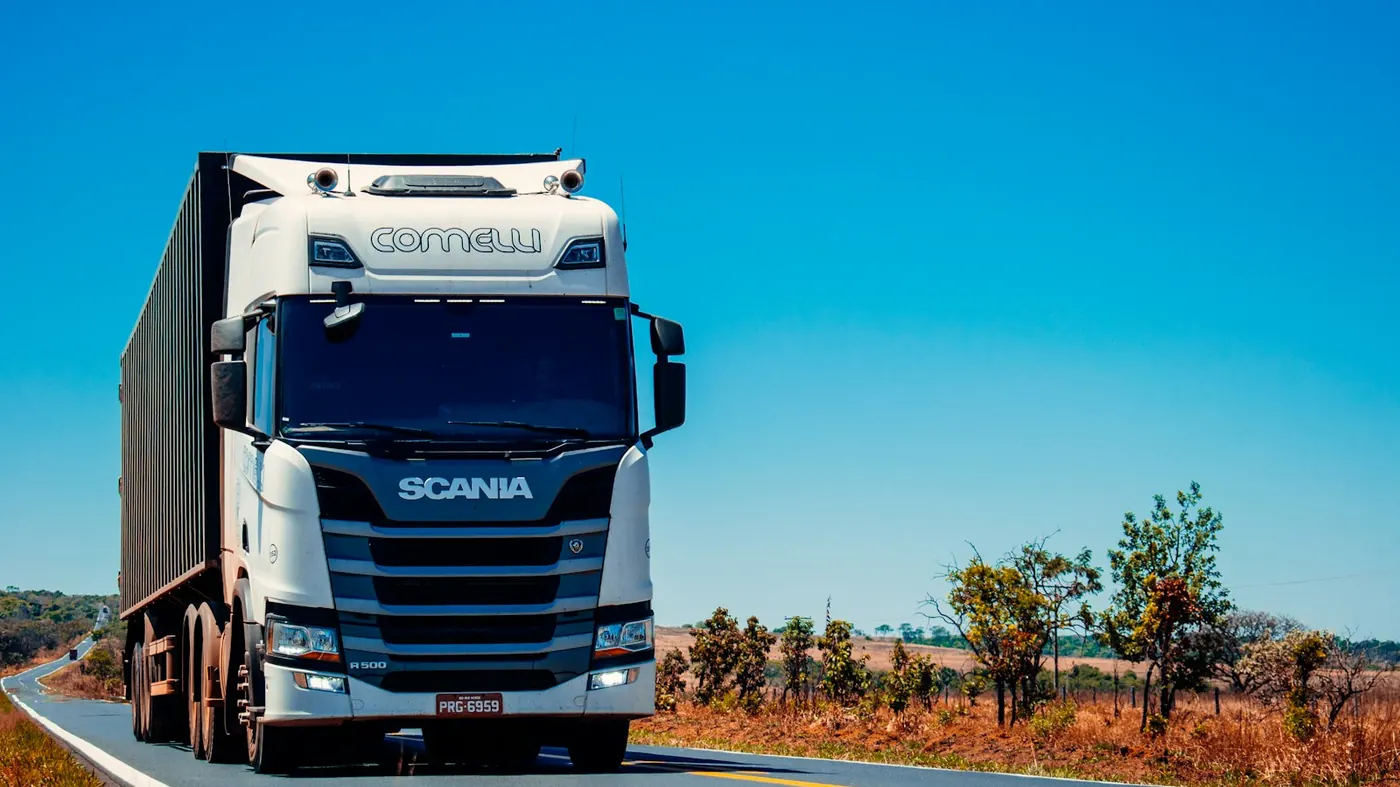 White Scania semi carrying a container on an open road